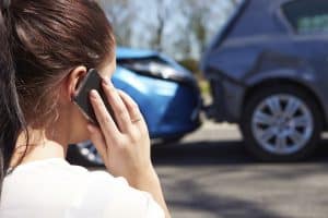A woman calls her insurance company after an auto collision