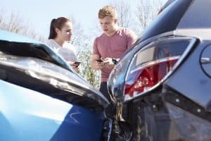 Two drivers exchange auto insurance information after a collision